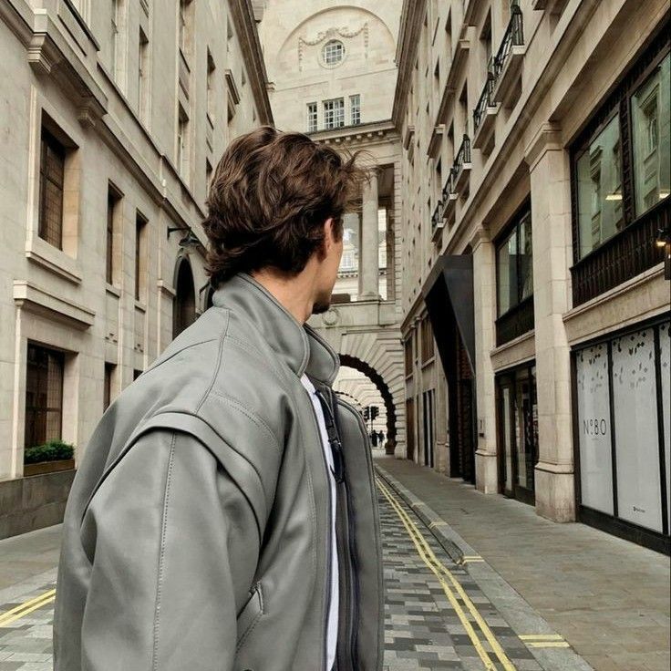 a man walking down a street next to tall buildings