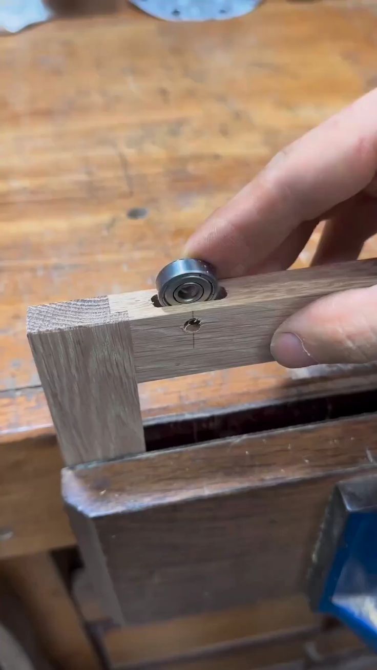 a person holding a piece of wood with a small metal object on top of it