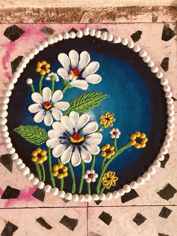 a painted plate with flowers on it sitting on a tile floor next to black and white tiles