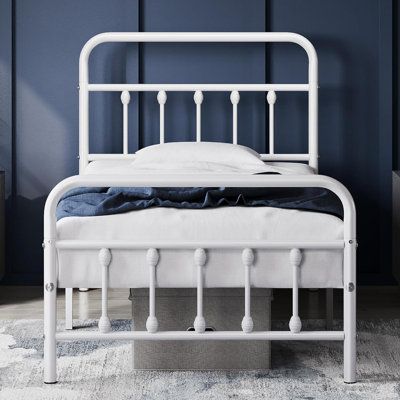 a white metal bed frame in a room with blue walls and rugs on the floor