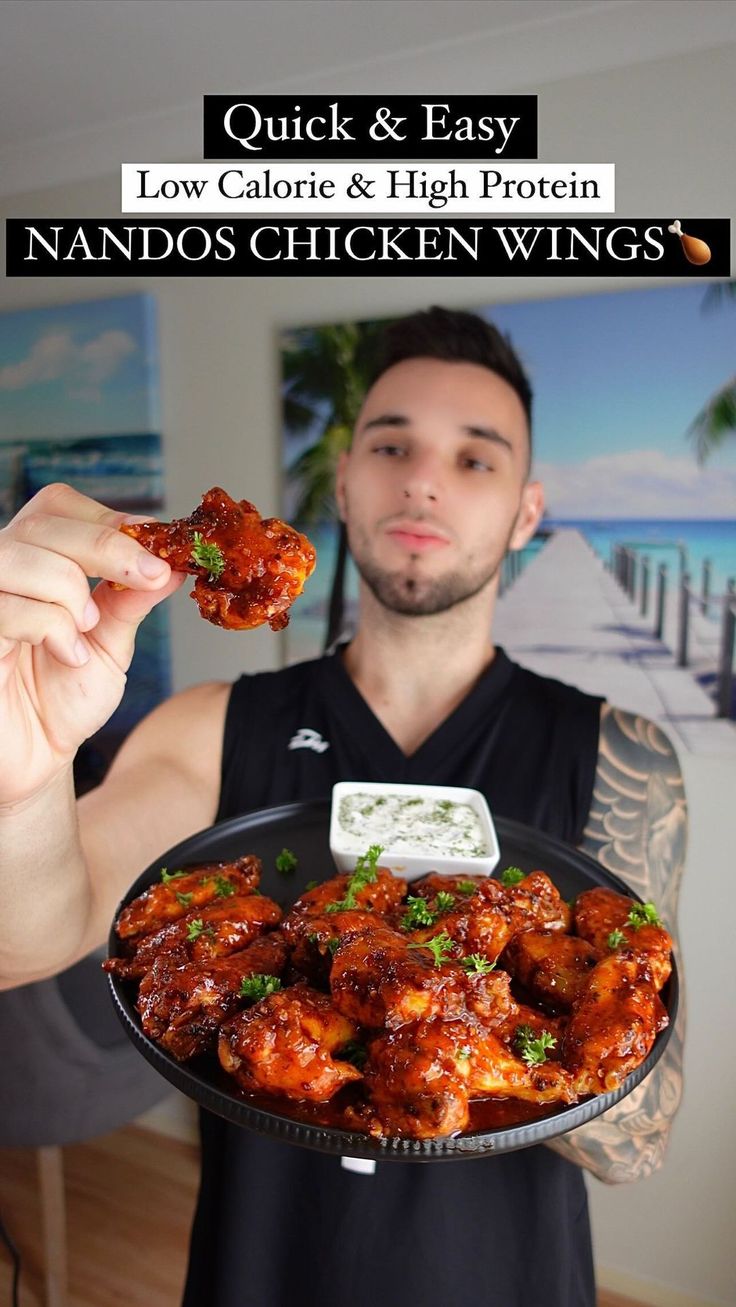 a man holding a plate with chicken wings on it