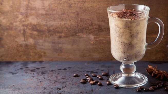 a glass mug filled with coffee and topped with cinnamon