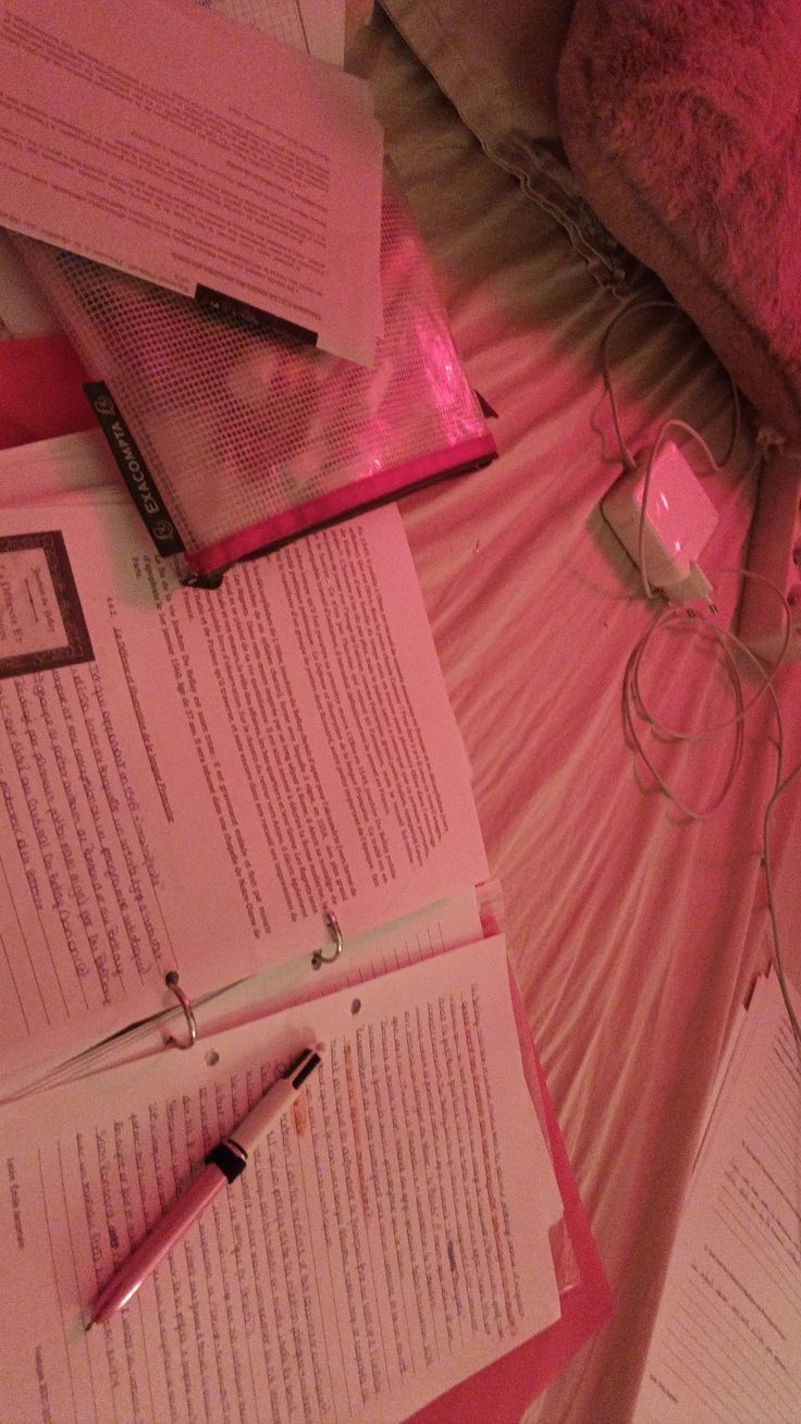 several papers are spread out on a bed with pink sheets and headphones next to them