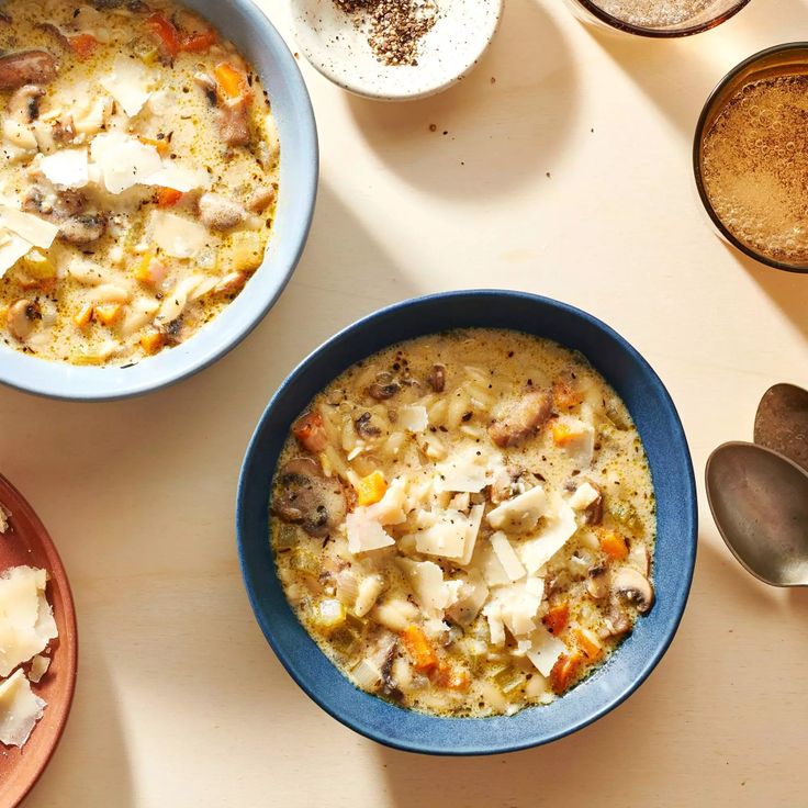 three bowls of food on a table with spoons and cups next to each other