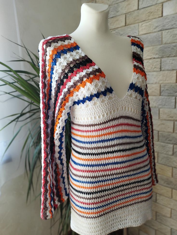 a crocheted sweater is displayed on a mannequin