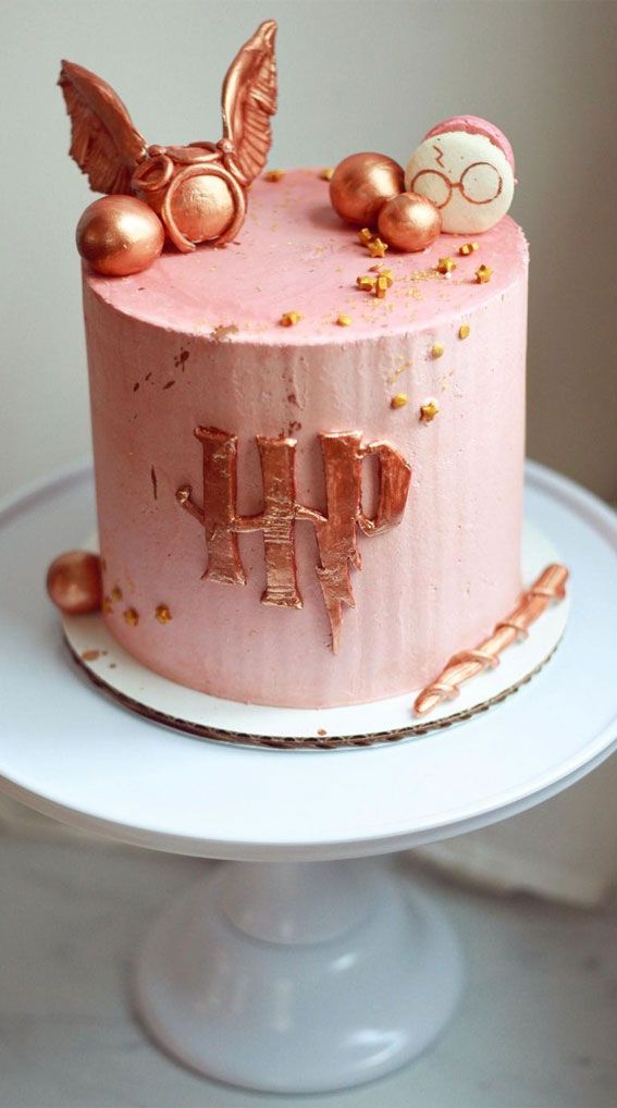 there is a pink cake with gold decorations on it