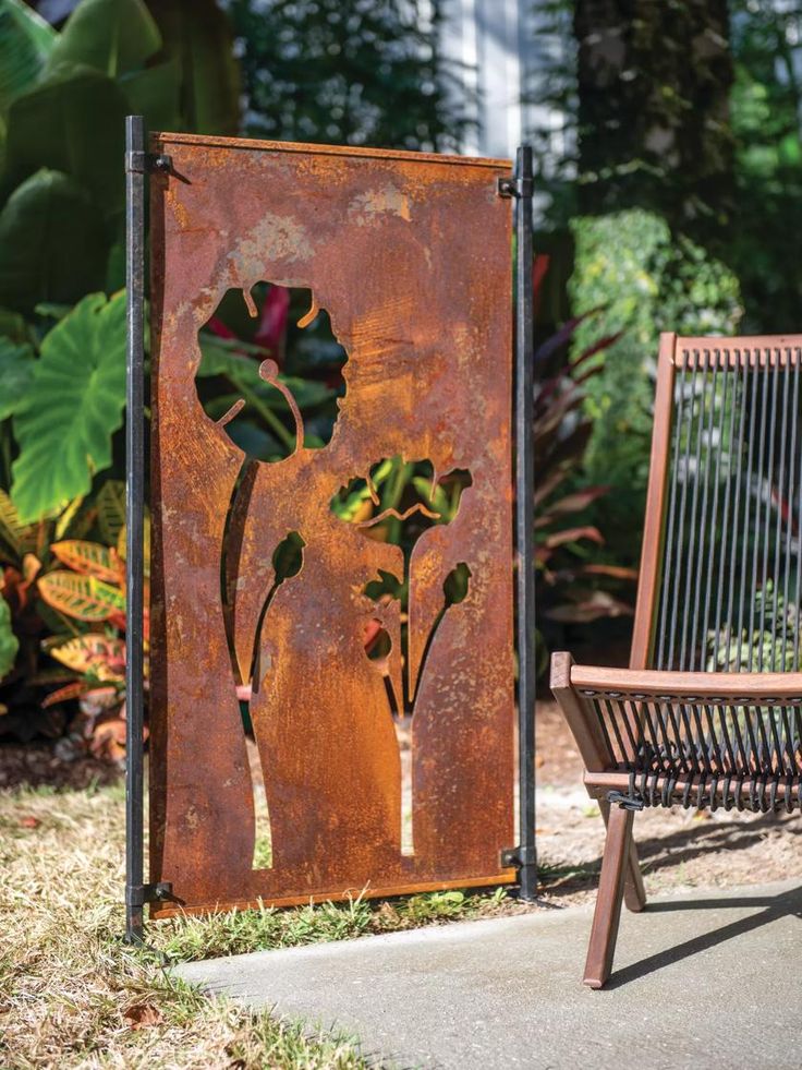 an old rusted metal sign with flowers on it next to a wooden bench in the garden