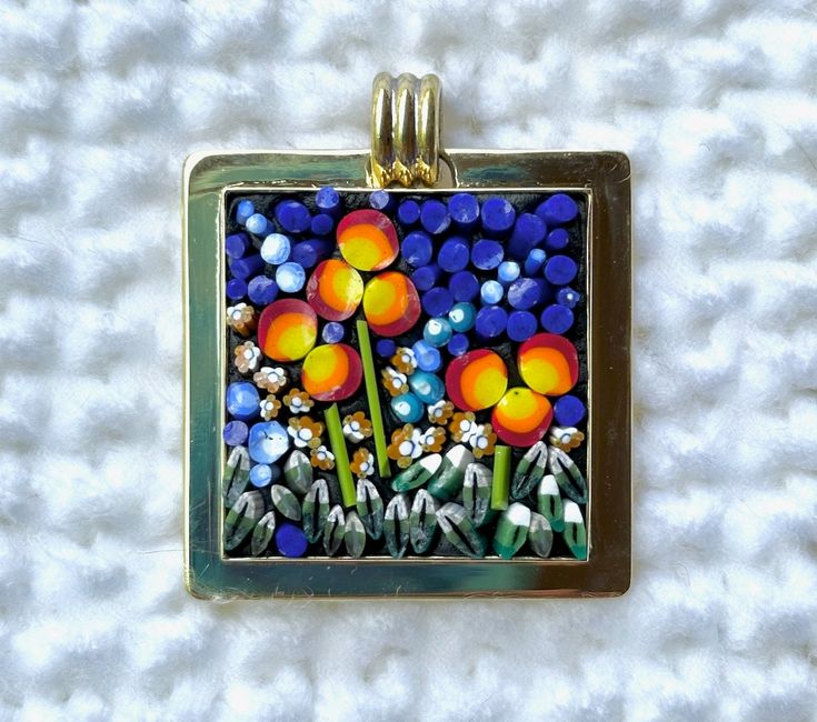 a square pendant with flowers painted on it