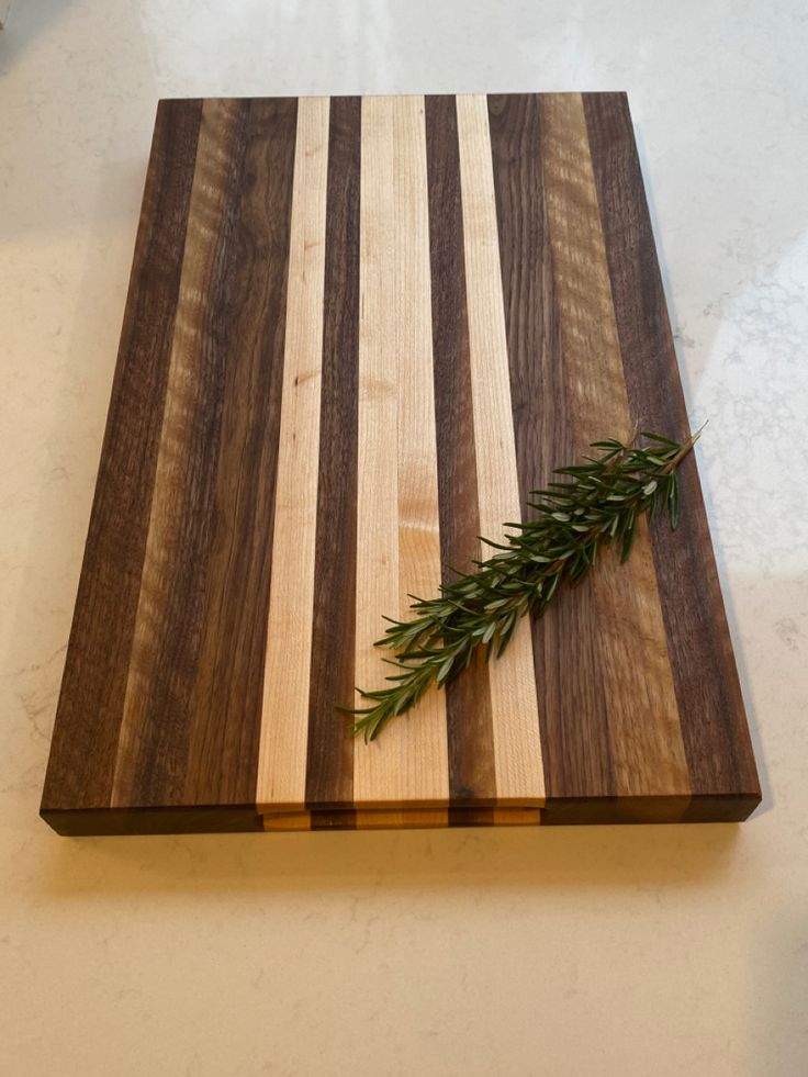 a wooden cutting board topped with a green plant on top of a white countertop