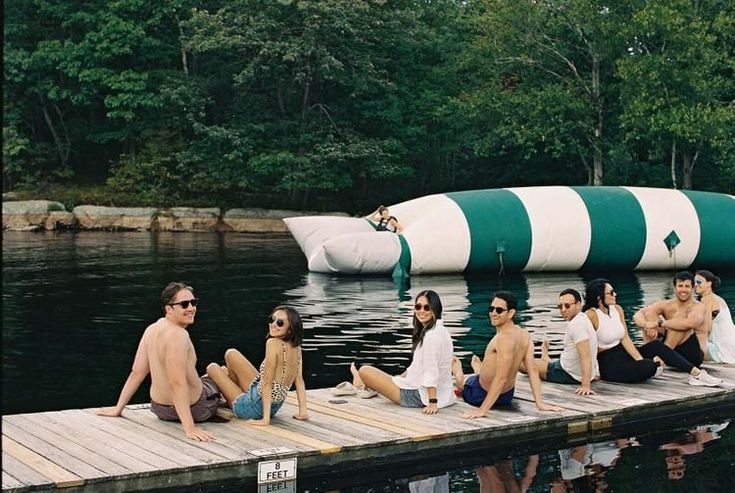 a group of people sitting on top of a wooden dock