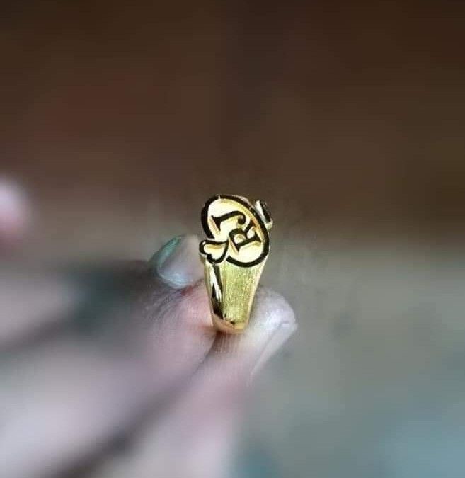 a person holding a gold ring with an om sign on it