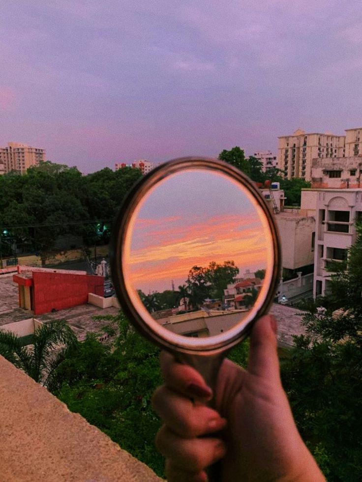 a person holding a magnifying glass up to their face in front of a cityscape