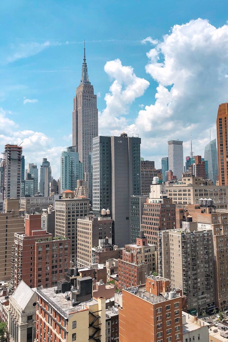 the city is full of tall buildings under a blue sky with white clouds in the background