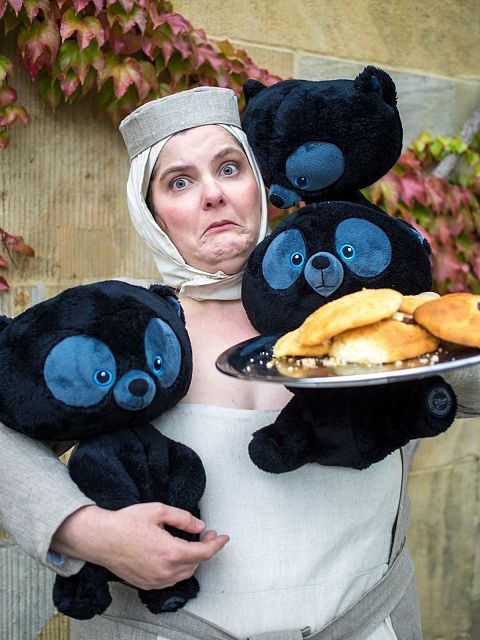 a woman holding three black stuffed animals on top of a plate