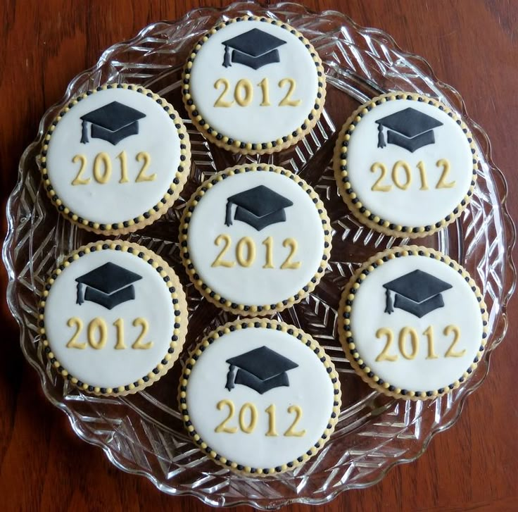 cookies decorated with graduation caps and numbers on a glass platter for the 2012 - 2012 year