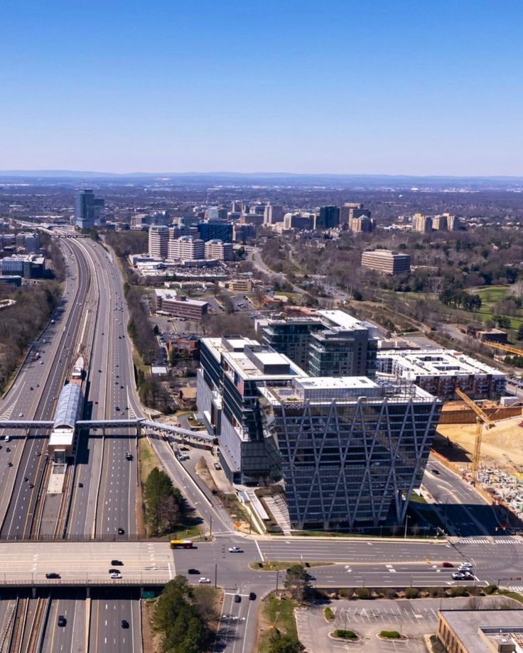 an aerial view of a city with lots of traffic on the road and buildings in the background