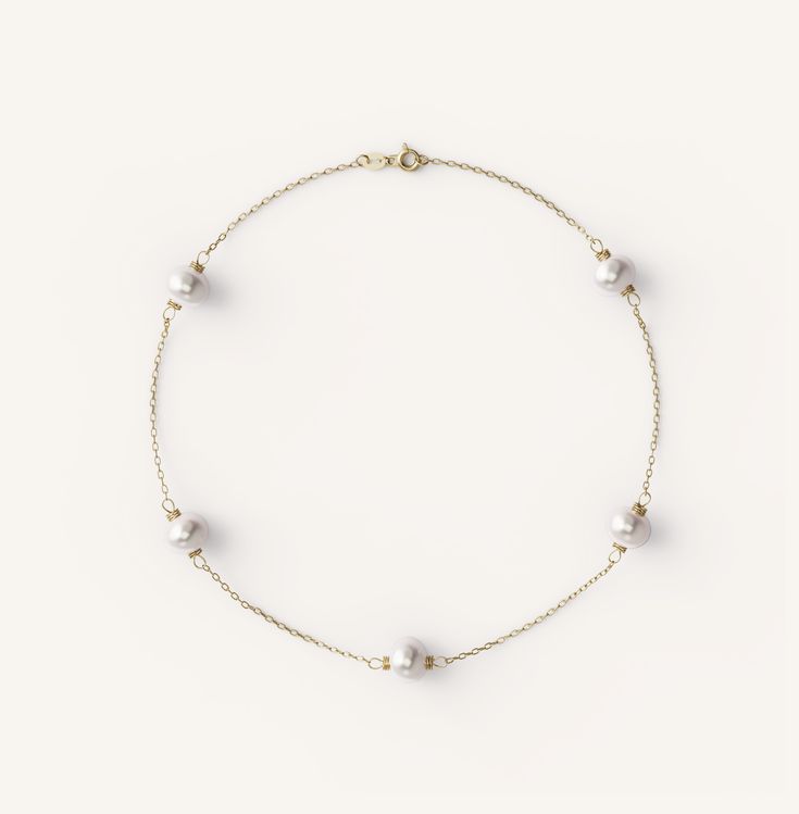 a bracelet with pearls and gold beads on a white background, the bead is attached to