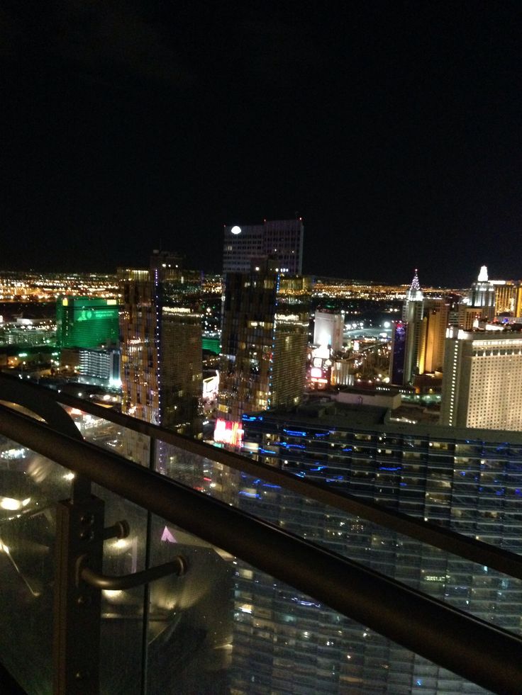 a balcony overlooking the las vegas strip at night with city lights and skyscrapers in the background