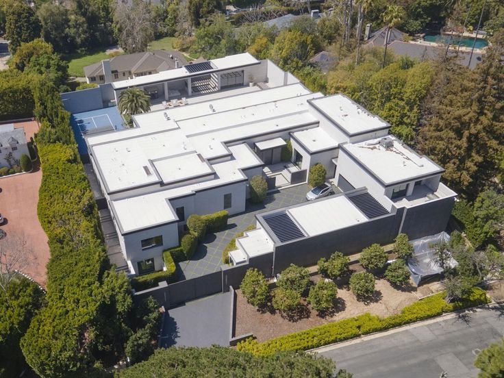 an aerial view of a large house with lots of trees and bushes around it,