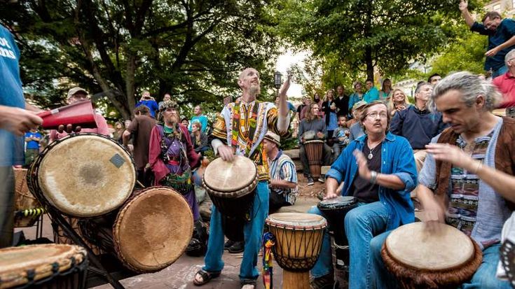 a group of people playing musical instruments in front of a crowd on the side walk