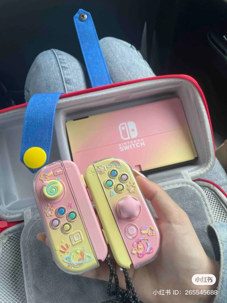 someone holding two nintendo wii game controllers in their hand, and the other one has a video game controller attached to it