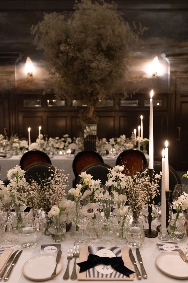 the table is set with white flowers and candles for an elegant dinner party or special event