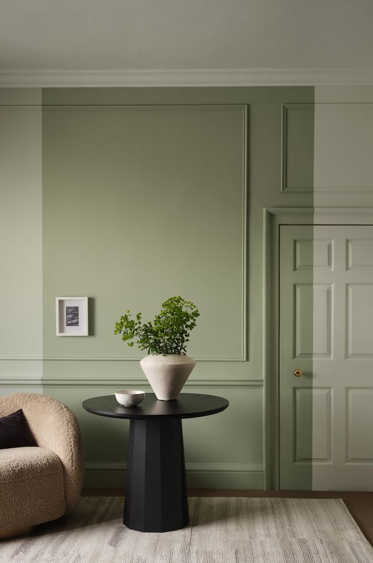 a living room with green walls and a small plant on the table in front of it