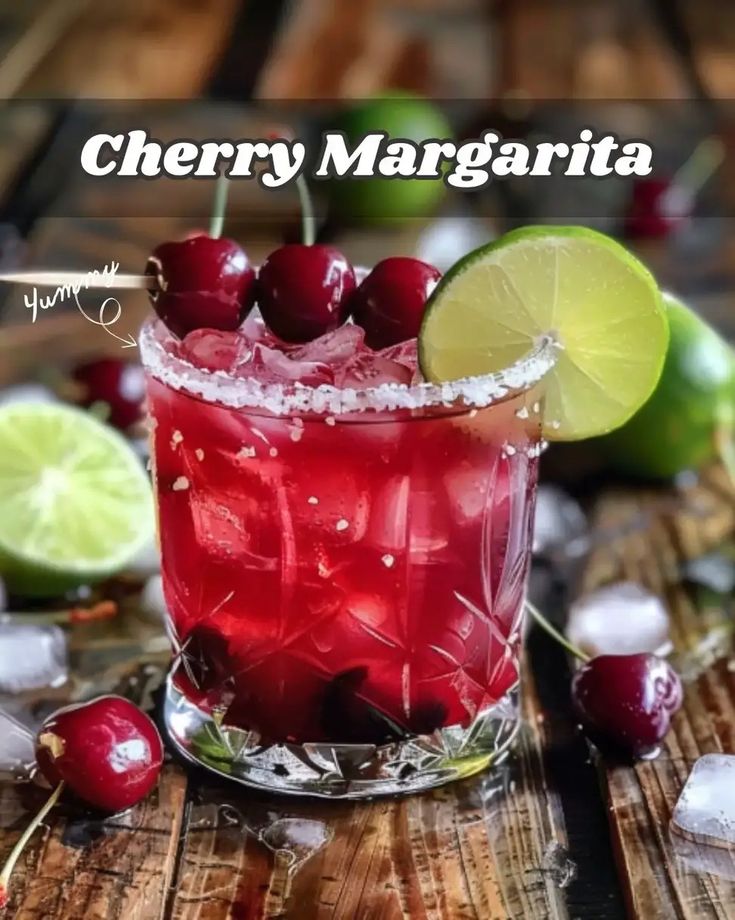 a cherry margarita with lime and ice on a wooden table next to some cherries