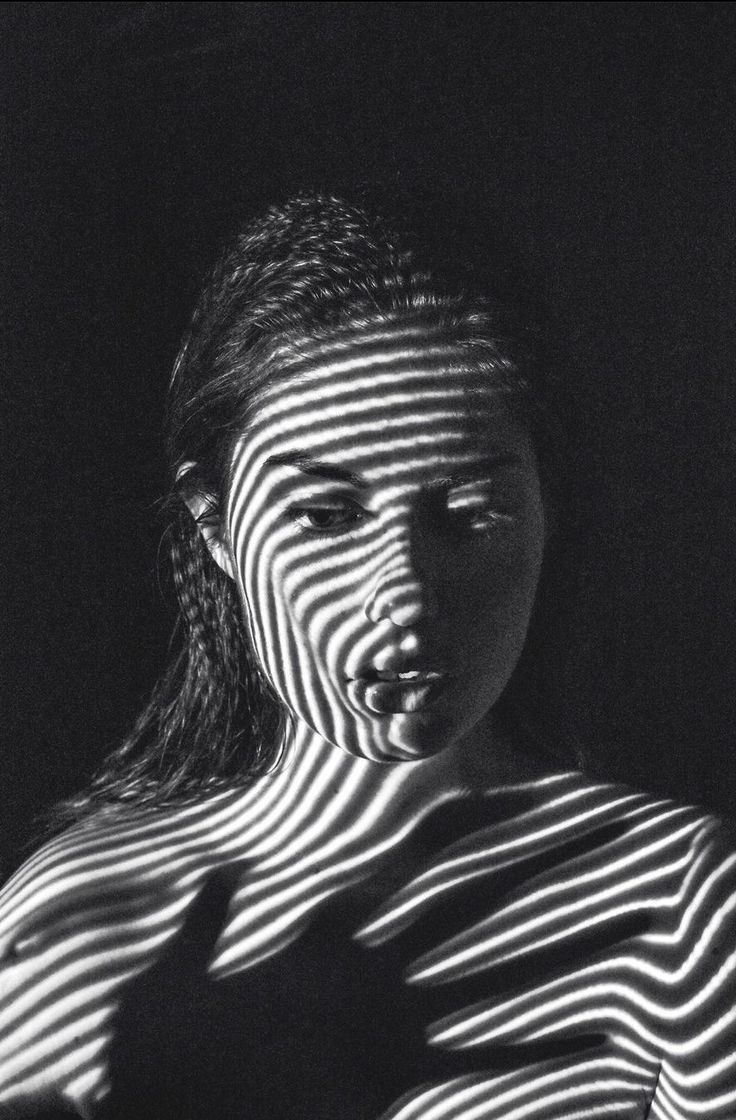 a woman's face is reflected in the light from her shadow, while she holds her hand up to her chest