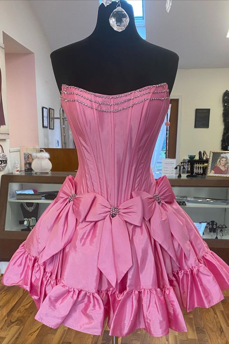 strapless pink A-line short homecoming dress with bows #homecomingdress #homecoming2024 #hocodress #winterformal2025 #graduationdress #dancedress #partydress #winterformaldress #fallball #balldress #highschoolball #juniorpromdress #pageantdress #cocktaildress #minidress #partydress #sweet16dress #birthdaydress #concertoutfit Strapless Ruffle Dress For Quinceanera, Strapless Dress With Corset Back For Quinceanera, Strapless Quinceanera Dress With Corset Back, Fairytale Party Fitted Corset Dress, Fairytale Fitted Corset Dress For Party, Satin Ball Gown Dresses For Quinceanera, Satin Dress For Quinceanera, Satin Dress With Sweetheart Neckline For Quinceanera, Satin Quinceanera Dress With Sweetheart Neckline