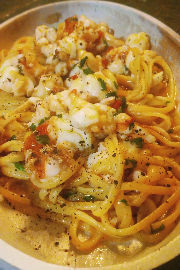 a bowl filled with pasta and shrimp on top of a table