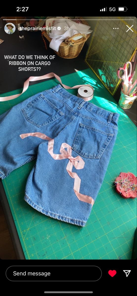 a pair of jean shorts sitting on top of a green cutting board next to scissors