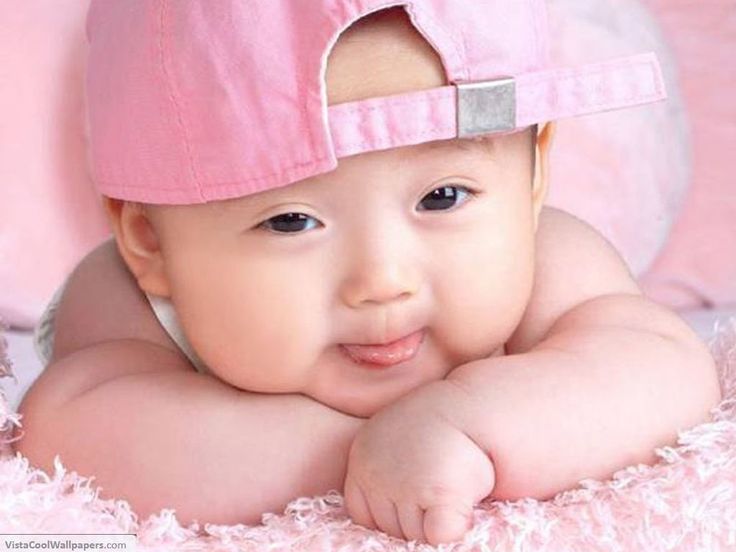 a baby wearing a pink hat laying on top of a bed