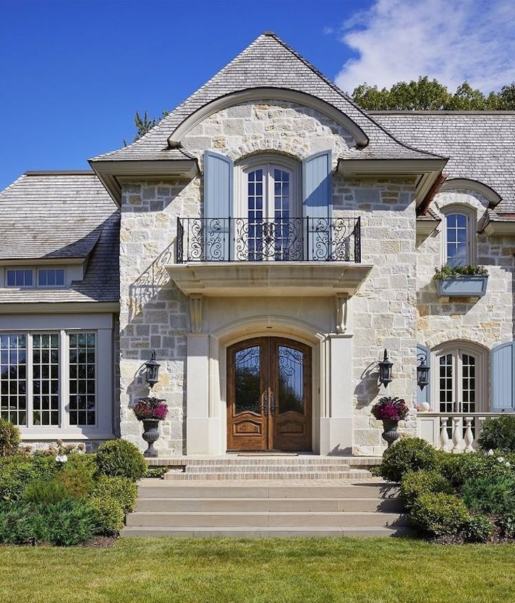 a large stone house with blue shutters on the front door and windows in the side