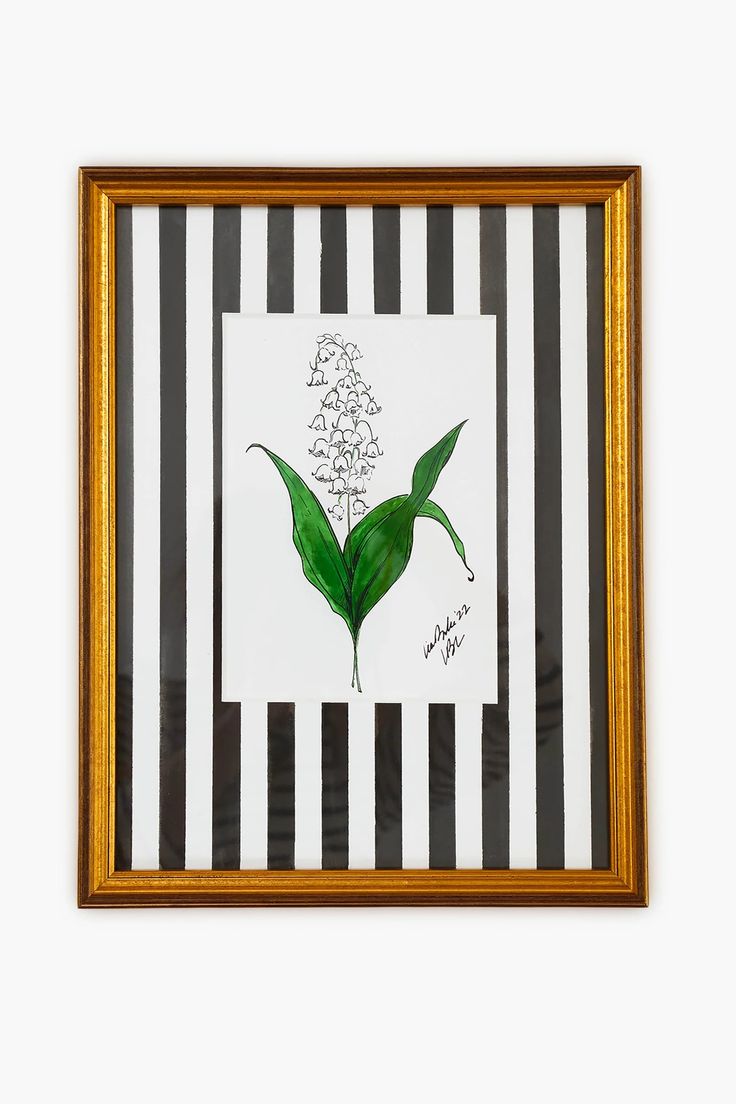 a painting with green leaves on black and white striped paper in a gold framed frame