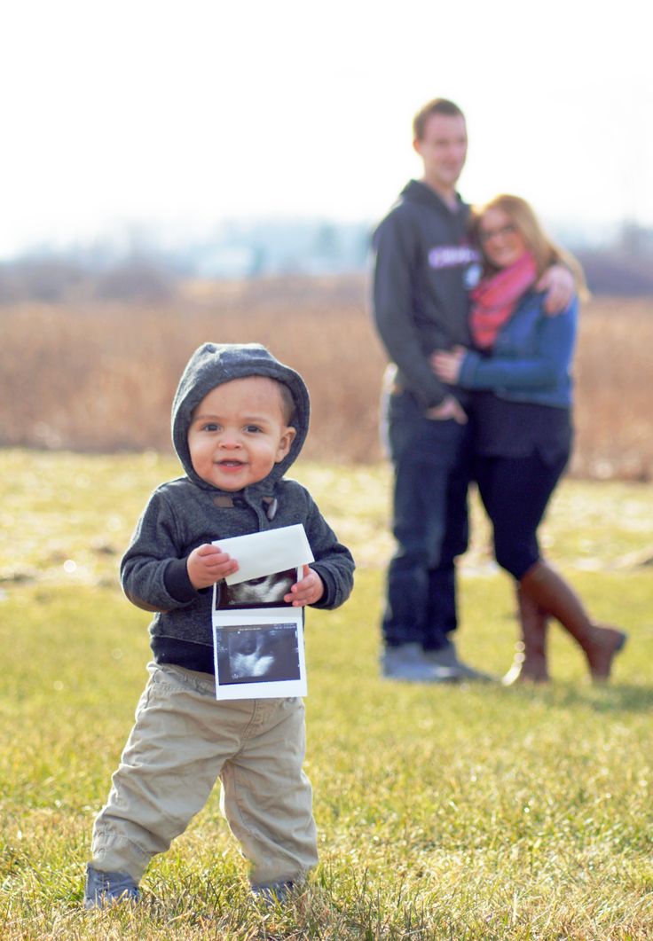 a young boy holding a photo in front of his family