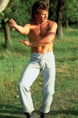 a man with no shirt on standing in the grass