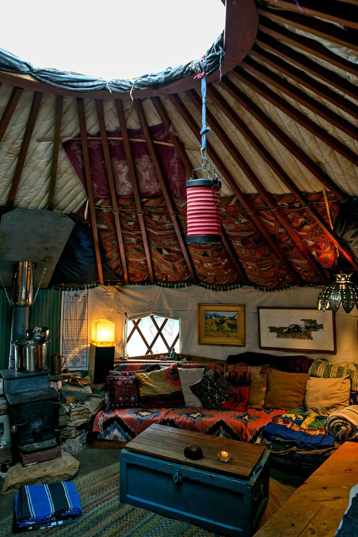 a living room filled with lots of furniture under a wooden roof next to a fire place