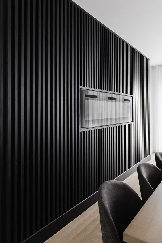 a long table with black chairs in front of a wall