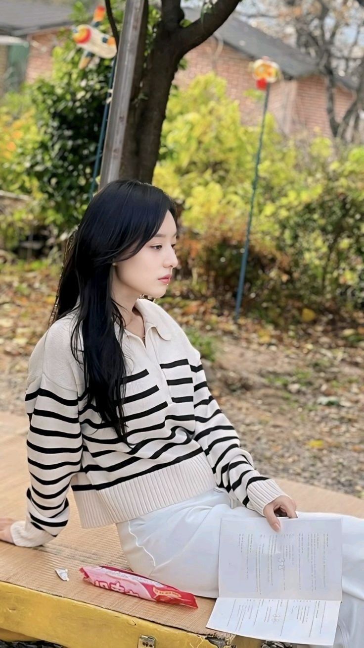 a woman sitting on top of a wooden bench