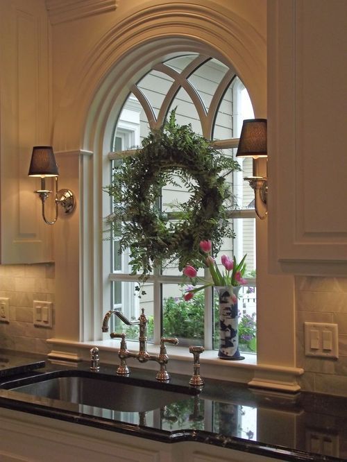 a kitchen with an arched window, sink and wreath on the countertop in front of it