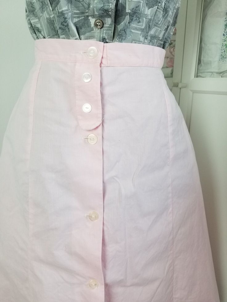 "Pretty pink sturdy cotton skirt. The fabric looks like it has a hint of a white pinstripe in the weave. This skirt buttons up and has a faux button placket at the top, where it uses snaps. small to medium waistband and a line shape. Label reads, Kermess\" Good to fair vintage condition. General, minor signs of wear. Two small abraded holes the size of a pen tip. 3 very small light rust spots (near/at waistband). Measurements Waist: 27\" Hips: Up to 41\" Length: 27.5\"" Seersucker Skirt, Dress And Jacket Set, Button Up Skirts, Henderson Nv, Antique Clothing, Beautiful Skirts, Cotton Skirt, Small Light, Dress Suits