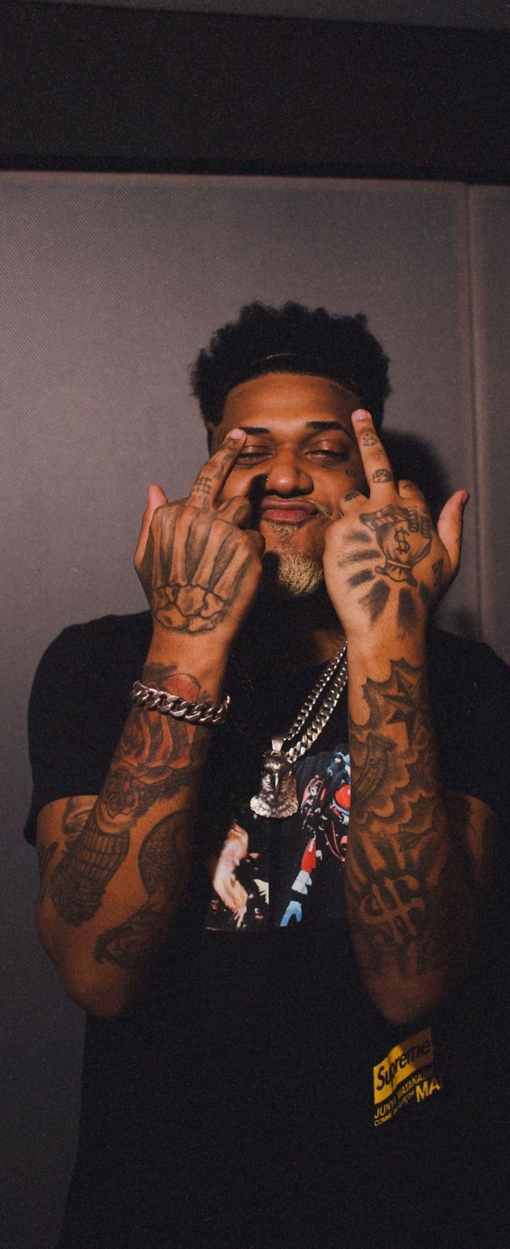 a man holding his hands to his face with tattoos on both sides and fingers above his eyes