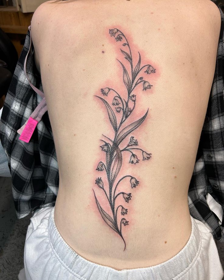 a woman's lower back tattoo with flowers on her left side ribcage