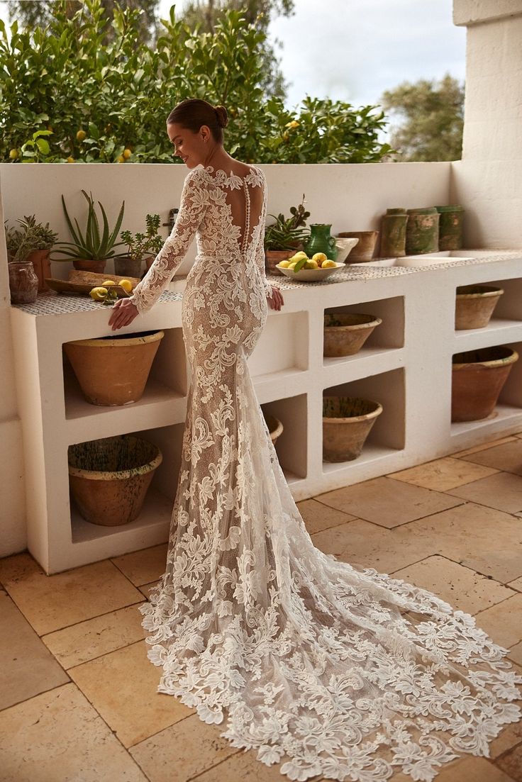 a woman in a white wedding dress standing on a tiled floor next to potted plants