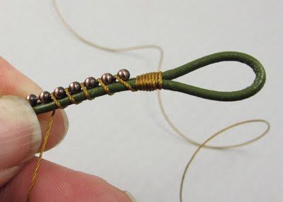 a person is holding a green string with gold beads on it and threading the ends