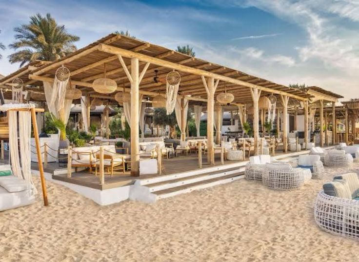 an outdoor dining area on the beach with chairs and umbrellas