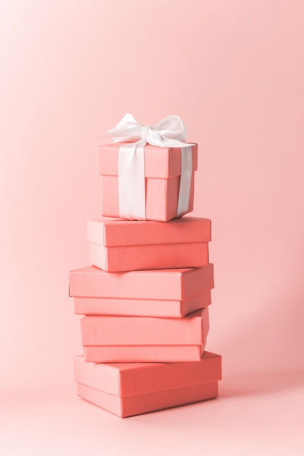 a stack of pink books with a white bow on top, against a light pink background