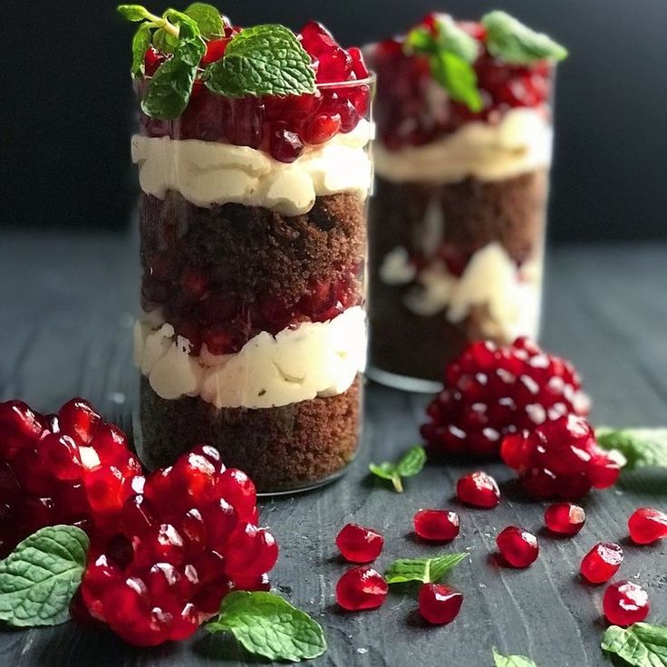 two desserts with strawberries and whipped cream on top are sitting in small glass jars