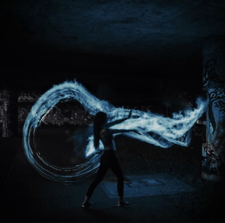 a woman is dancing in the dark with blue fire and water swirling around her head